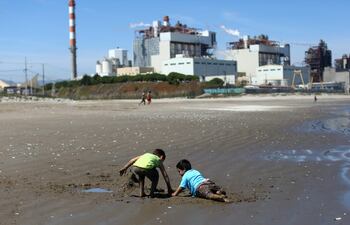 (En esta foto de archivo tomada el 8 de octubre de 2019, niños juegan en la arena de la playa Las Ventanas junto a la planta termoeléctrica AES Gener en Puchuncaví, región de Valparaíso, Chile.