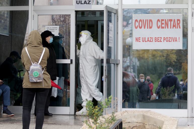 Unas personas esperan fuera de un centro de atención para pacientes con covid-19 en Sarajevo, Bosnia.