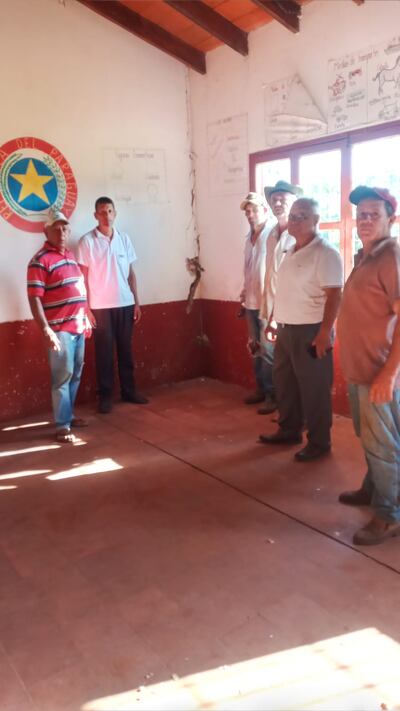 Padres de familia en una de las salas de clase con paredes agrietadas en la Colonia Mandu'arã