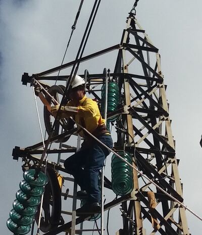 Técnicos de la empresa eléctrica trabajan en la torre de una línea de transmisión.