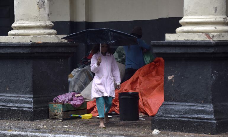 Descalza, y con un maltrecho paraguas, una niña camina frente a la Estación Central del Ferrocarril, en el microcentro asunceno.