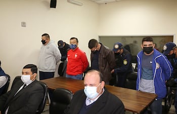 Agentes policiales retiran las esposas a sus camaradas acusados por extorsión a narcos, en la sala de juicio oral y público.