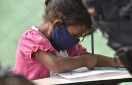 Sin posibilidad de dar clases presenciales, una niña recibe refuerzo escolar en una improvisada escuelita del Bañado Norte, atendida por voluntarios.