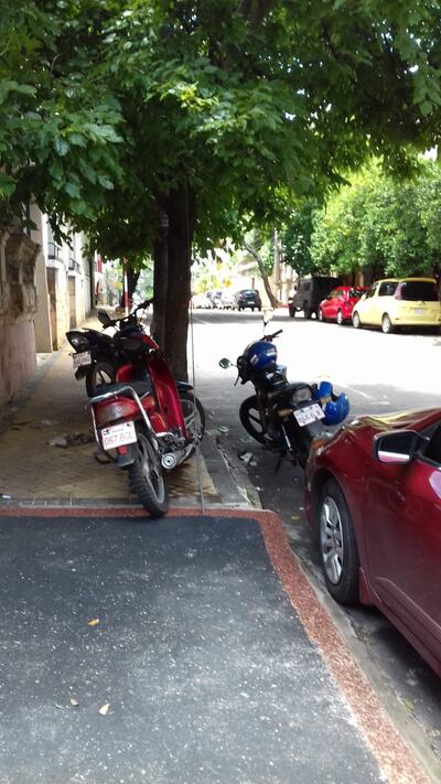 Para aprovechar la sombra del árbol los motociclistas dejan su vehículo en la vereda que se encuentra en Iturbe casi Manuel Domínguez, frente a Dirección de Vigilancia Sanitaria. Los que por allí caminan tienen que sortear baldosas levantadas y motos en su camino.