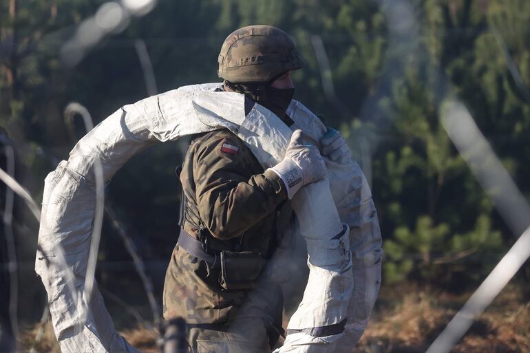 Un soldado polaco lleva rollos de alambre de púas para reforzar el cruce fronterizo con Bielorrusia en la región de Grodno.