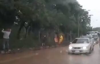Personas agarradas del alambrado para cruzar durante la lluvia