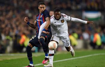 Raphinha, delantero del Barcelona, disputa el balón con Tyrell Malacia, defensor del Man. United