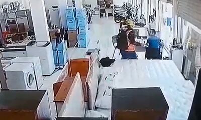 El delincuente desenfunda un revólver y apunta a uno de los empleados de la empresa.