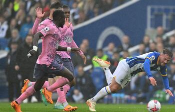 El argentino Alexis Mac Allister tropieza y va al suelo ante la presencia de tres jugadores del Everton durante el partido que Brighton perdió ayer de local por 5-1.