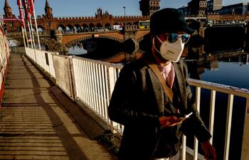 Un hombre usa máscara mientras camina junto al puente Oberbaum en Berlín, Alemania.