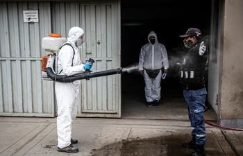 Un trabajador municipal desinfecta a un guardia de seguridad en Lima, Perú.