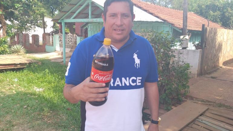 Enrique Villagra, mostrando la botella en la cual halló los restos de envoltorios. 