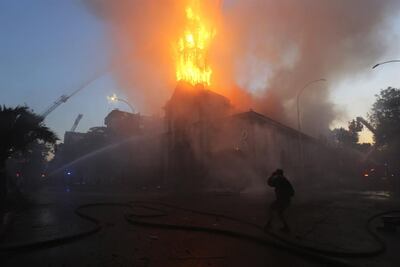 Bomberos trabajan en la extinción del incendio de la Iglesia de La Asunción hoy domingo, en los alrededores de la Plaza Italia de Santiago (Chile), rebautizada popularmente como "Plaza Dignidad", durante el primer aniversario de las protestas que sacudieron todo el país austral y que tuvieron su epicentro en la capital chilena.