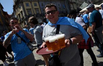 Un hincha del Manchester City carga una bandeja con vasos de cerveza.