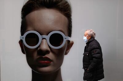 Un hombre con mascarilla caminaba este martes por delante de una óptica en una calle de A Coruña, en una jornada en la que el Consejo de Ministros aprueba el decreto que eliminará, a partir del miércoles, la obligación de llevar mascarilla en los espacios cerrados salvo centros, servicios y establecimientos sanitarios, incluidas las farmacias, y el transporte público, en tanto que en los trabajos, decidirán las propias empresas.