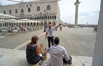 Una agente alerta a los turistas sobre la llegada de una marea alta, en la zona de la plaza de San Marco, en Venecia, Italia.