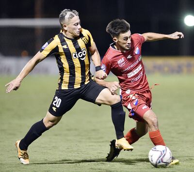 Con el “corte” de pelo de debutante se lo ve al aurinegro Milton Maciel en la puja por la pelota con Sebastián Vargas.