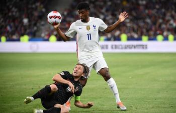 El capitán de Croacia, Luka Modric, disputa desde el piso el balón con el delantero francés Kingsley Coman.