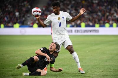 El capitán de Croacia, Luka Modric, disputa desde el piso el balón con el delantero francés Kingsley Coman.