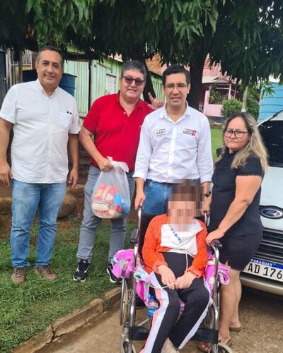 Los candidatos César "Landy" Torres (centro) y Pedro Adán Ovelar (izq.) junto con dos pobladoras. En la imagen también está un hombre de remera roja con la bolsa de alimentos.