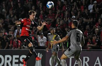 Cristian Bernardi, delantero de Colón, salta en procura del balón ante el arquero de Peñarol, Damián Musto, durante el partido jugado anoche en Santa Fe, Argentina.