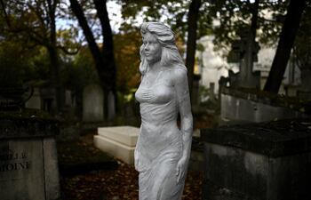 Un estatua a escala humana de una mujer sin identificar adorna una tumba vacía en el cementerio de Pere Lachaise en París.