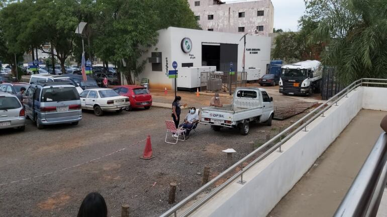 Un paciente con vía, afuera del hospital, siendo asistido por su esposa