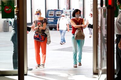 Dos mujeres desinfectan sus manos antes de acceder a un centro comercial de la madrileña calle Preciados.