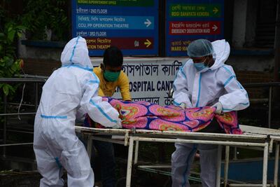 Trabajadores llevan el cadáver de una víctima del coronavirus, en el hospital del distrito de Siliguri, India.