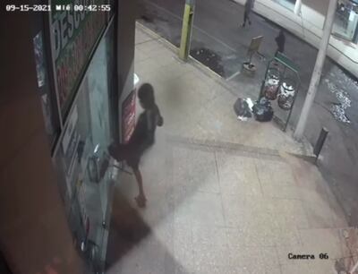 Uno de los adolescente rompe con una piedra la puerta de vidrio de la farmacia para ingresar al sitio.