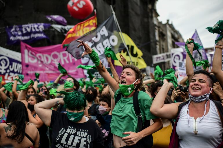 Demonstrators celebrate with green headscarves - the symbol of pro-abortion activists - outside the Argentine Congress in Buenos Aires on December 11, 2020, after legislators passed a bill to legalize abortion. (Photo by RONALDO SCHEMIDT / AFP)