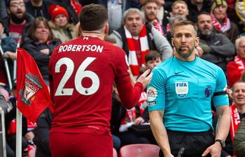 Andy Robertson (i) discute con el árbitro asistente Constantine Hatzidakis, durante el partido que Liverpool y Arsenal empataron el domingo 2-2 por la Liga Premier.
