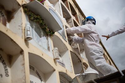 Trabajadores de un cementerio en Huanuco, Perú, cargan un féretro a un nicho.