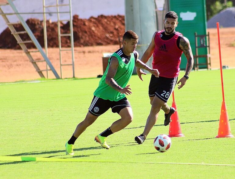 Derlis González (26 años) se hace del esférico y Jorge Eduardo Recalde (28 años) lo ve pasar, en la práctica de Olimpia. “Pollo” Recalde tiene una suspensión de cuatro partidos.