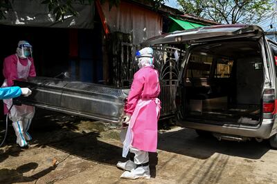 Esta foto tomada el 17 de octubre de 2020 muestra a voluntarios usando equipo de protección personal (PPE) mientras cargan un ataúd que contiene el cuerpo de un residente sospechoso de morir por el coronavirus COVID-19 en una camioneta para llevarlo al hospital en Yangon, Birmania.