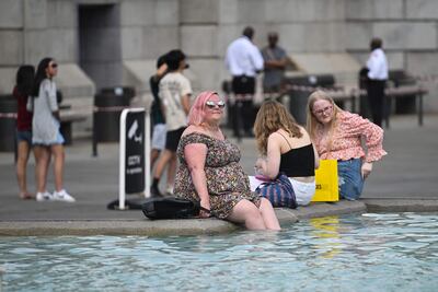 Varias personas se refrescan en la fuente de Trafalgar Square, en Londres.