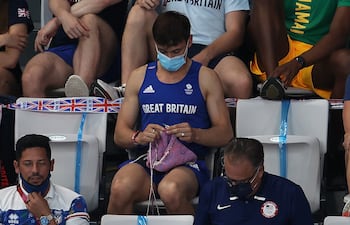 El saltador británico tejiendo un suéter, sentado en una tribuna.