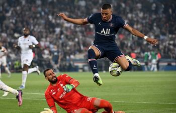 Kylian Mbappé salta para evitar el contacto con el arquero Marc-Aurele Caillard, del Metz, durante el partido de ayer que el París SG ganó 5-0 con triplete del astro francés.