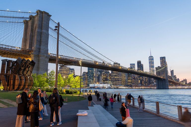 Personas pasean por el parque de Dumbo frente al icónico puente de Brooklyn, que une los distritos de Manhattan y Brooklyn,.
