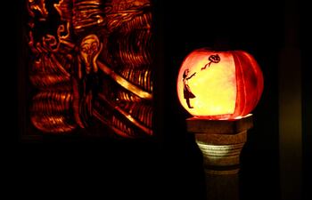 Una calabaza iluminada con la figura de "La niña con globo", del artista Bansky, y de fondo una obra inspirada en "El grito", de Munsk, forman parte de la decoración de una casa neoyorkina por Halloween.