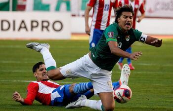 No dejando pasar a Marcelo Moreno Martins, el capitán boliviano, el del Paraguay, Gustavo Gómez en acción ayer en el partido en La Paz. (AFP)