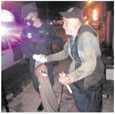 Instante en que el hombre mayor es ayudado por un agente policial para ser llevado a un lugar de atención.