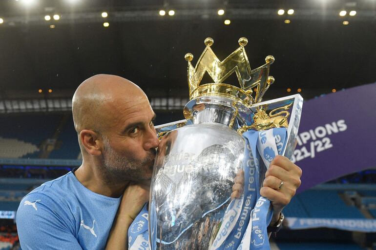 El técnico español del Manchester City, Pep Guardiola, celebra con el trofeo de la Premier League en la cancha después del partido de fútbol de la Premier League inglesa entre el Manchester City y el Aston Villa en el estadio Etihad de Manchester, noroeste de Inglaterra, el 22 de mayo de 2022.