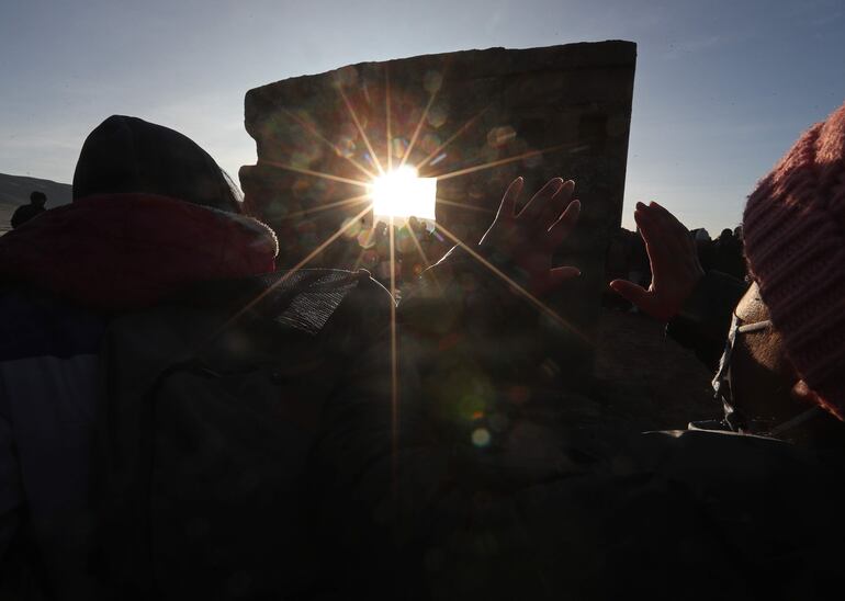 Un grupo de personas recibe los primeros rayos del sol durante la tradición de espera del inicio del Año Nuevo Andino, hoy, en Tiahuanaco (Bolivia). (EFE)