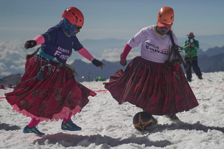 Cecilia Llusco y Senobia Llusco, mujeres indígenas aymaras miembros de las Cholitas Escaladoras de Bolivia Warmis, juegan un partido de fútbol a unos 6.000 m, en la última zona plana antes de hacer cumbre en la montaña Huayna Potosí de 6.088 metros, cerca de El Alto, Bolivia.
