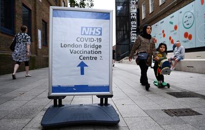 Peatones caminan junto a un cartel que indica el camino a un centro de vacunación contra el Covid en Londres, Inglaterra.
