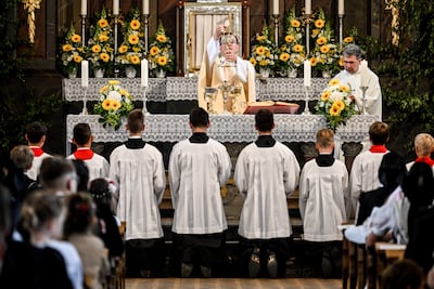 Monaguillos se arrodillan para rezar en la celebración de Corpus Christi en Crostwitz, Alemania.