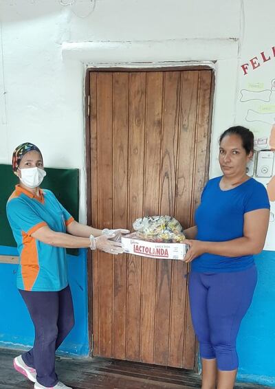 Una madre de familia recibe la leche y las galletitas en la escuela de Bahía Negra.