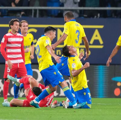 Santiago Arzamendia celebra arrodillado su gol ante la euforia de sus compañeros del Cádiz y la decepción de jugadores del Granada.