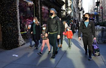 Personas con máscaras protectoras caminan junto a las ventanas navideñas en Saks Fifth Avenue el 29 de noviembre de 2020 en la ciudad de Nueva York.